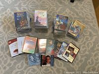 Stack of unopened Animated Bible Story DVDs from Nest Complete Learning Systems with titles 'Animated Bible: Abraham and Isaac,' 'The Animated Bible,' 'Animated New Testament: Stories in Heaven,' and 'Animated Bible Stories for Children' visible. Additional loose DVDs with various Christian themes spread below.