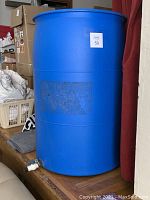 Full view of large blue plastic barrel for water storage with label indicating 50 gallons.
