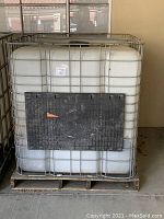 Front view of the 275 gallon water storage container inside its protective metal cage and on a wooden pallet base.