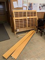 Wooden headboard, footboard, side rails and support feet arranged in room corner.