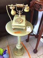 Rotary dial marble styled phone resting on round marble stand table, showcasing the whole lot items.