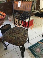 Full view of one wood and metal chair with upholstered seat and wooden backrest with vertical grooves and metal scrollwork.