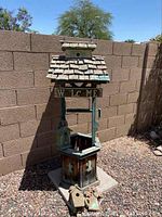 Front view of the wooden water well decor with one bird house attached and two bird houses on the ground.