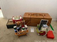 Full view of sewing cabinet, pin cushion holder with threads, and several sewing tins and boxes