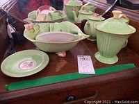 Photo showing the full tea set including the leaf-shaped serving bowl, teapot, cup, saucer, and plates on a wooden surface.