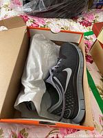 Nike Free 4.0 V2 running shoe inside original orange Nike box with white paper wrapping, showing details of shoe upper and sole.