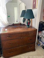 Front view of antique wooden dresser with mirror and green ceramic lamp on top, showing overall condition and matching style.