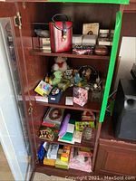 Four shelves filled with assorted decorative items, plush toys, boxes, purses, stationery, and a wristwatch.