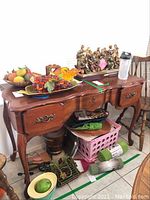Front view of wooden side table with decorative items on top and various items underneath.