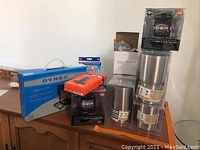 Lot showing dash cams, tumblers, Fire Stick, picture frame, and car hooks arranged on wooden surface