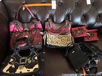 Seven larger bags and pile of small black pouches displayed on sofa