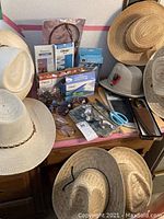 Overview of hats, sunglasses, office supplies including scissors and letter opener, two maps, and more on a table