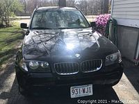 Front exterior view of black 2006 BMW X3 showing kidney grilles, headlights, hood, roof rails and Massachusetts license plate.