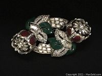 Front view of Coro Duette brooch showing red enameled flowers, green leaves with rhinestones, and silver metal frame.