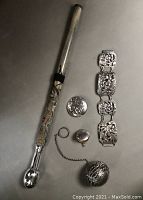 Photo showing the entire lot on a grey background including the umbrella handle, bracelet, brooch, locket, and tea infuser.