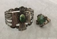 Photo showing front view of detailed thunderbird cuff bracelet with oval green center stone and matching rustic green stone ring.