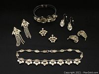 Full lot displaying all jewelry pieces on a black background including crown pins, earrings, bracelet, and necklace.