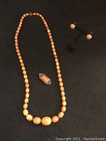 Full view of necklace, brooch and earrings laid out on black background