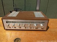 Full front and top view showing wood veneer cabinet, aluminum front panel, top vents and power cord.