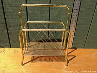 Front view of the vintage brass bamboo style mid-century record album stand showing its mesh shelf and bamboo-style frame.
