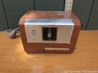 Front view of vintage Puritron Model F40 air purifier showing brown body, silver mesh front, toggle switch, vent with adjustment knob, and power cord.