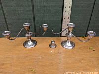 Pair of Gorham three-arm candelabras side by side, one with a detached arm screw shown between them on the table.