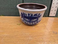 Front view of stoneware mixing bowl showing blueberry basket and blueberry decoration in cobalt blue on light gray background, dark brown glazed interior, placed next to a ruler for size reference.