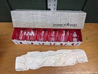 Full view of six crystal tumblers in original white box with red lining and protective paper wrapping.