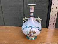 Front view of Victorian porcelain vase showing courting scene, ornate handles, and decorative patterns with ruler for scale.