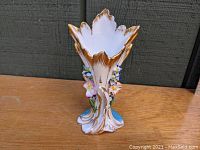 Front angle showing the vase's floraform shape, hand-applied flowers, and gold accents.