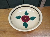 Top view of a cream-colored ceramic bowl decorated with a red pansy flower and green leaves, featuring a black rim band. Shows the single spaghetti bowl in excellent condition with minimal signs of use.
