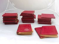 36 red hardcover classic literature books arranged in groups and stacks.