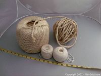 Four spools of twine and rope in varying sizes and thicknesses shown with measuring tape for scale