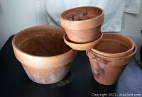 Three terra cotta pots arranged together on fabric background, showing natural earthy color and signs of use