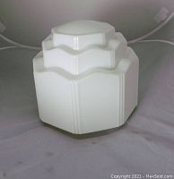Front and angled view of the white milk glass light fixture showing stacked Art Deco style tiers and smooth glossy surface