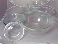 View of the largest to medium mixing bowls with one glass lid on top and additional lids nearby.