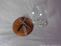 Photo showing underside of wooden base and three utensils inside the glass dome.