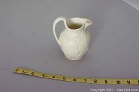 Full view of cream pitcher placed on flat surface with measuring tape showing size about 6 inches tall.