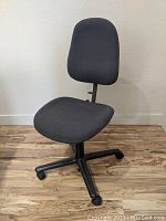 Front view of the black fabric upholstered vintage Herman Miller swivel office chair showing the contoured seat and backrest, plastic base with caster wheels.