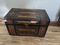 Front view of antique trunk showing leather, wood slats, metal reinforcements, handle and lock