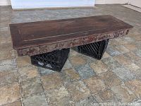 Full view of the rectangular wooden altar table top on milk crates showing surface wear and carved edge details.
