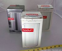 Three boxes of Bodum replacement tempered glasses for French press coffee makers, showing brand and size.