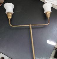 Two-light antique table lamp with brass finish and twin milk glass shades on a black surface.