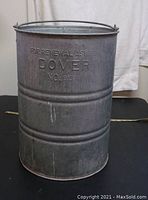 Front view of galvanized steel ash can showing embossed text and bail handle