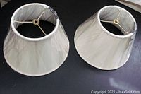 Two beige lamp shades viewed from top revealing the metal frame.