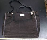 Full view of the black canvas over the shoulder portfolio bag with handles and shoulder strap, showing size with a ruler.