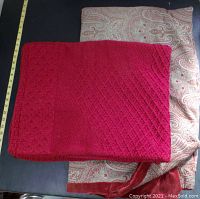 Both throw blankets folded and laid flat on a dark surface with measuring tape alongside to show size.