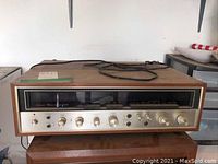 Front view showing wood cabinet top, silver faceplate, tuning dial and control knobs