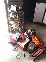Full view of all items showing the rack, various boxed tools, cables, and the hydraulic floor jack.