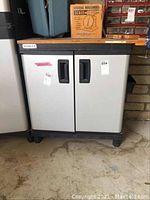 Front view of gray Stanley tool cabinet with double doors, black frame, and recessed handles, sitting on caster wheels on a concrete floor.